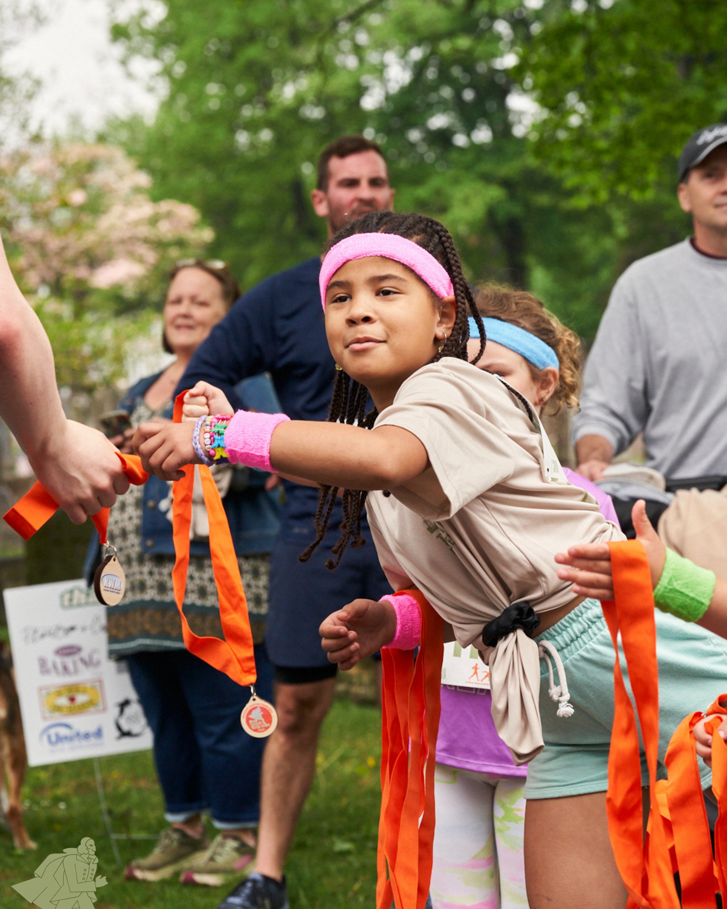 a young participant / volunteer handing out medals at the finish line