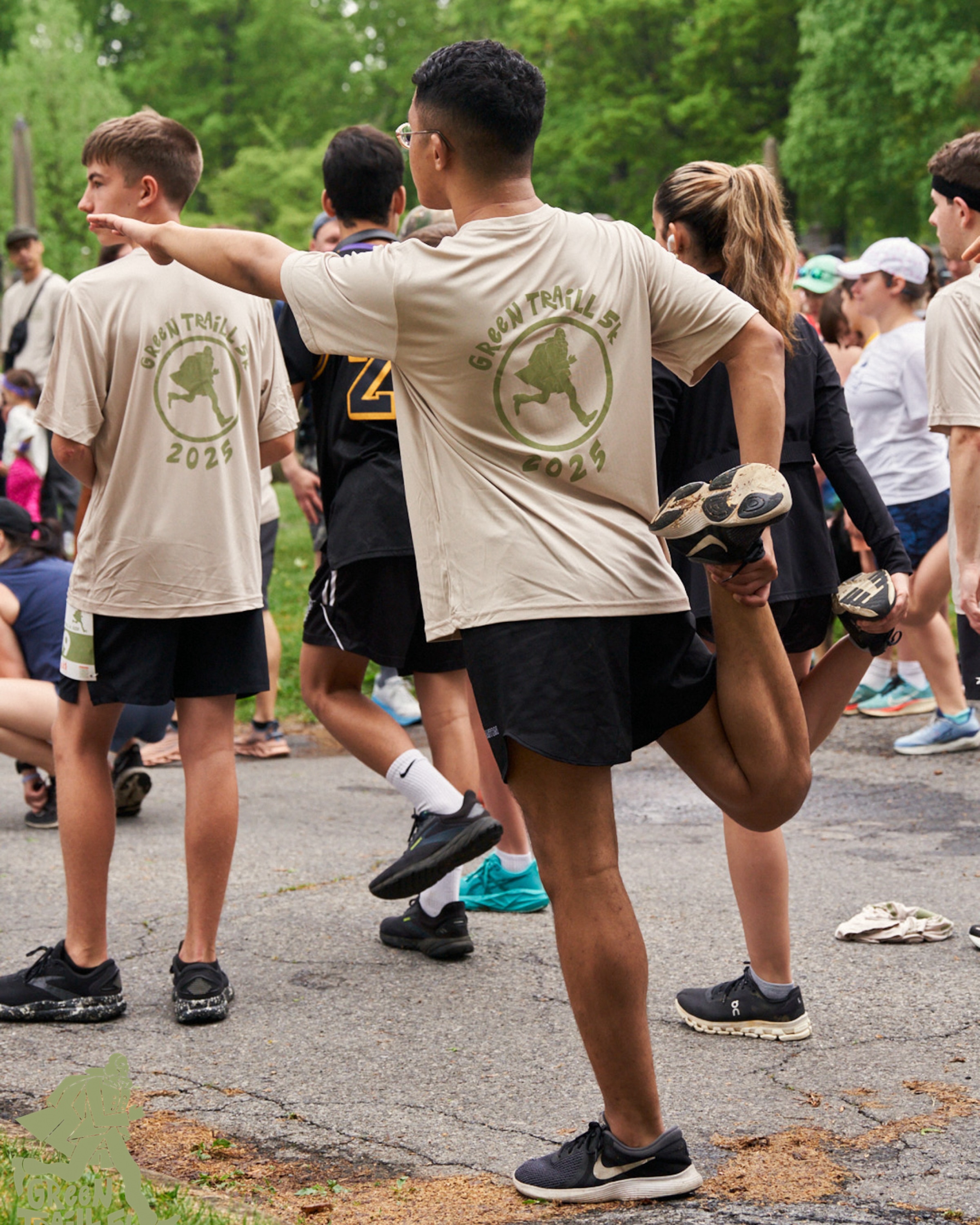 a participant warming up before the race, holding their leg and reaching out their arm in a stretch